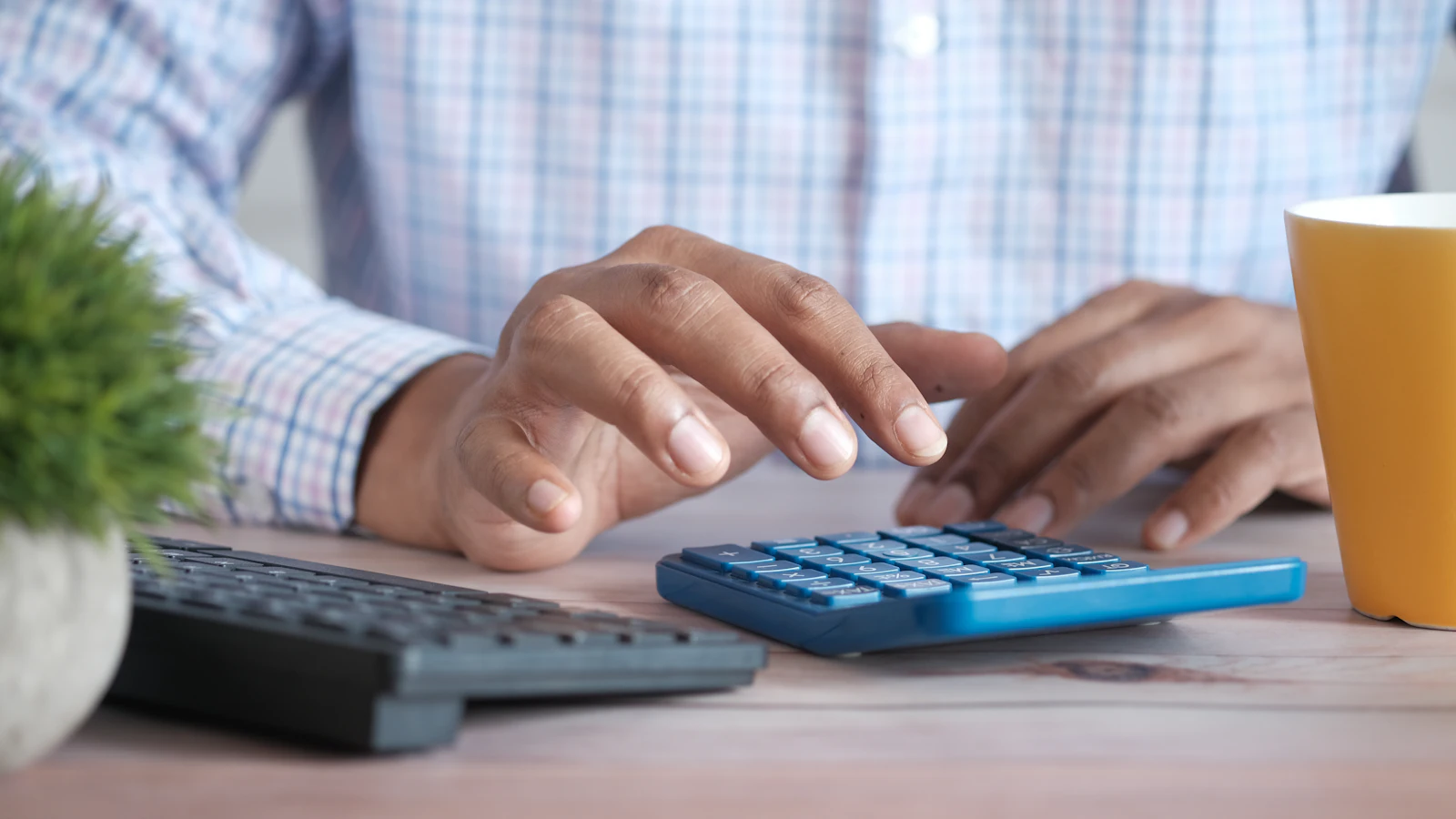 Travailleur autonome calculant ses impôts avec une calculatrice à son bureau