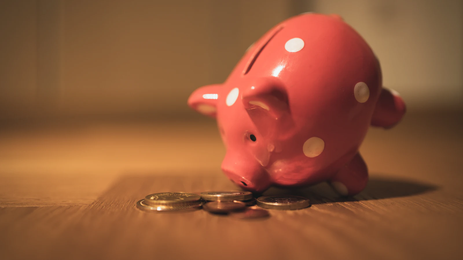 Tirelire en forme de cochon et pièces de monnaie sur une table en bois