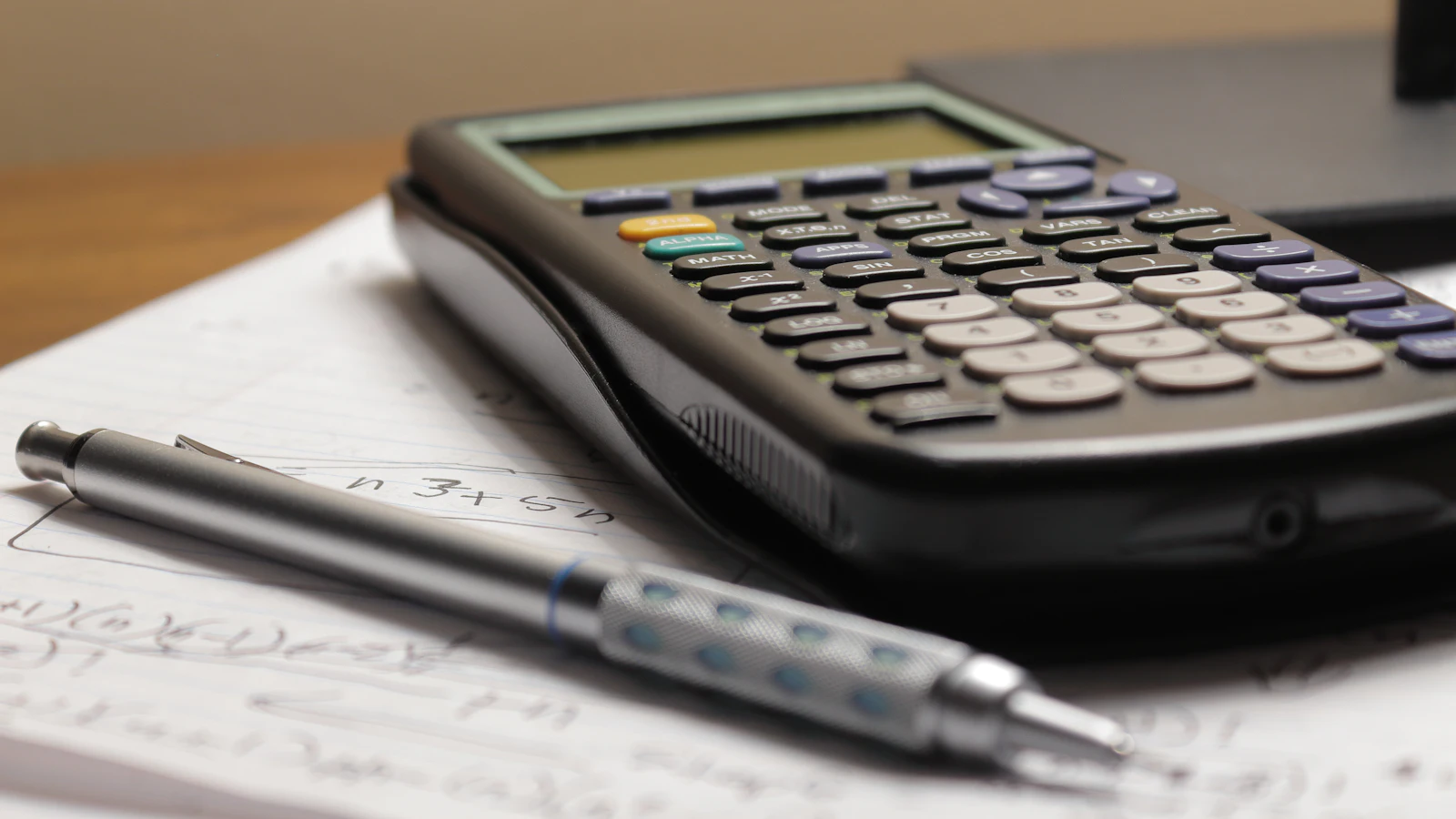 Calculatrice et crayon posés sur des feuilles de calcul pour préparer sa déclaration de revenus