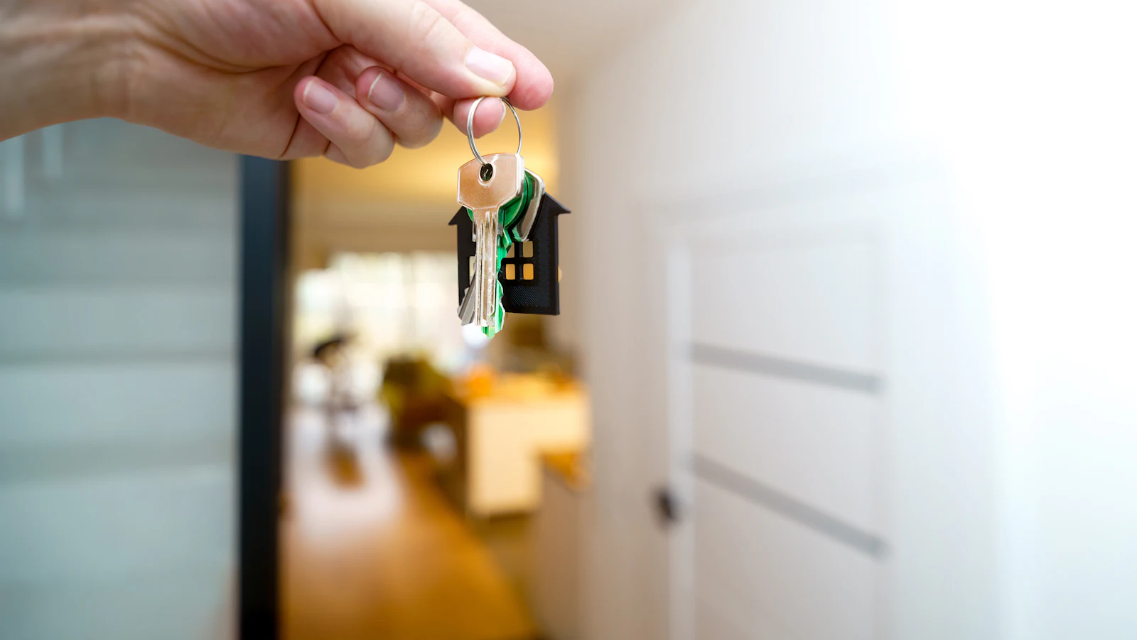 Main tenant les clés d'une première maison devant la porte d'entrée